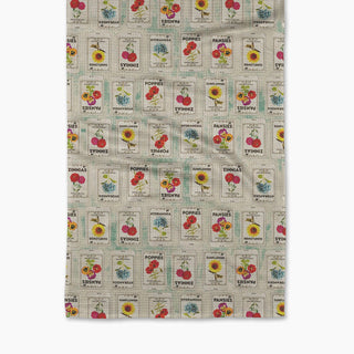 A multicolored kitchen towel with a geometric pattern featuring flower seed packs.