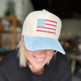 Person wearing a cap with a colorful pattern, indoors. Daisy USA flag hat