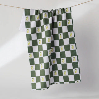 A kitchen towel with a green and white checkered pattern, each square containing a small yellow pear, hanging from a thin rope against a light gray background.