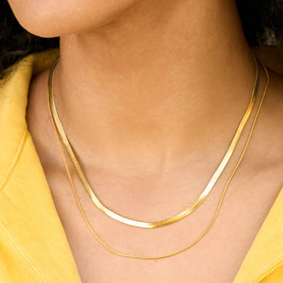 Close-up of a person wearing a gold necklace with a yellow top.