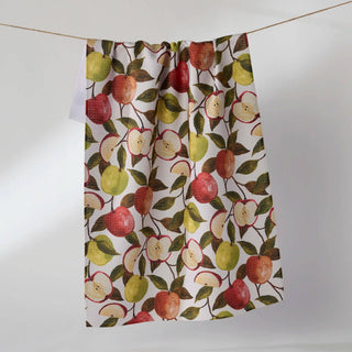 A kitchen towel with a watercolor-style apple pattern, hanging from a string against a plain light gray background.
