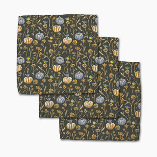 Two patterned dishclothes with pumpkins and flowers on a dark background