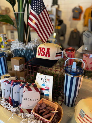 Display of patriotic merchandise including hats, tumbler, and books with American flag design.
