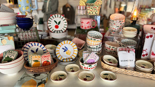 Display of decorative plates, mugs, and small containers on a table.