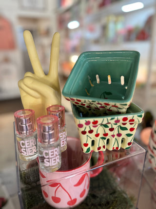 Decorative items including a ceramic basket with cherry design, small bottles, and a yellow hand making a peace sign.