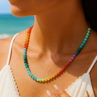 Woman wearing a colorful beaded necklace with a beach in the background. Rainbow Glow Stone Necklace