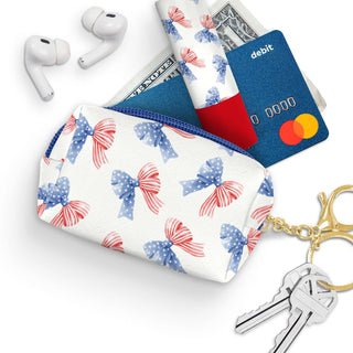 Small pouch with floral design, keychain, cards, and earbuds on a white background. Americana